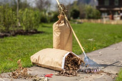 Hände binden einen vollen Papier-Abfallsack zusammen