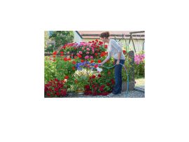 Glückliche Frau beim Gießen und Düngen von Blumen mit dem Aquamix Dossiergerät. Die Pflege der Pflanzen erscheint kinderleicht