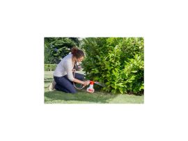 Glückliche Frau beim Gießen und Verteilen von Nematoden auf Blumen mit dem AquaNemix Dossiergerät. Die Pflege der Pflanzen erscheint kinderleicht